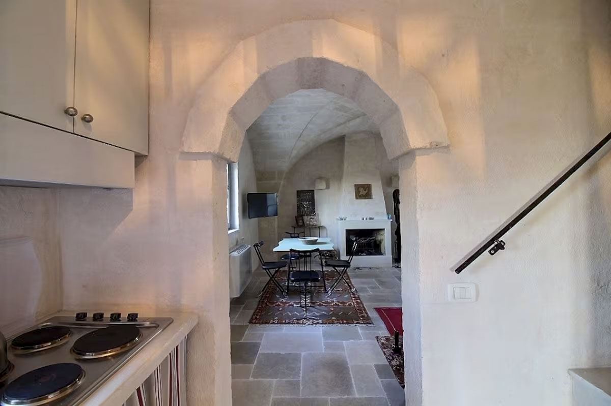 View from the kitchenette through the stone archway into the vaulted living room and dining area.