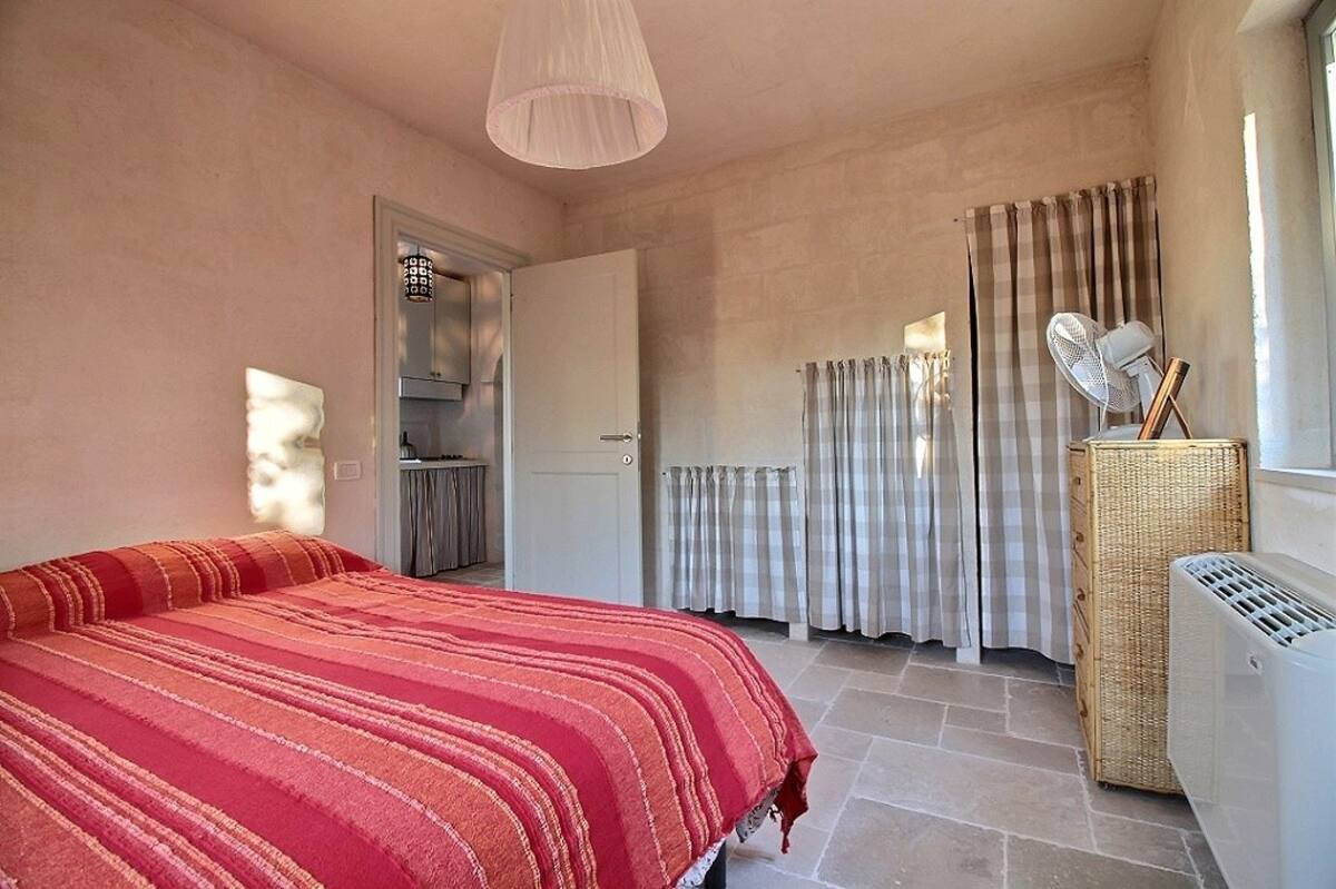 View from the main bedroom across the bed towards the open door leading to the kitchenette area.