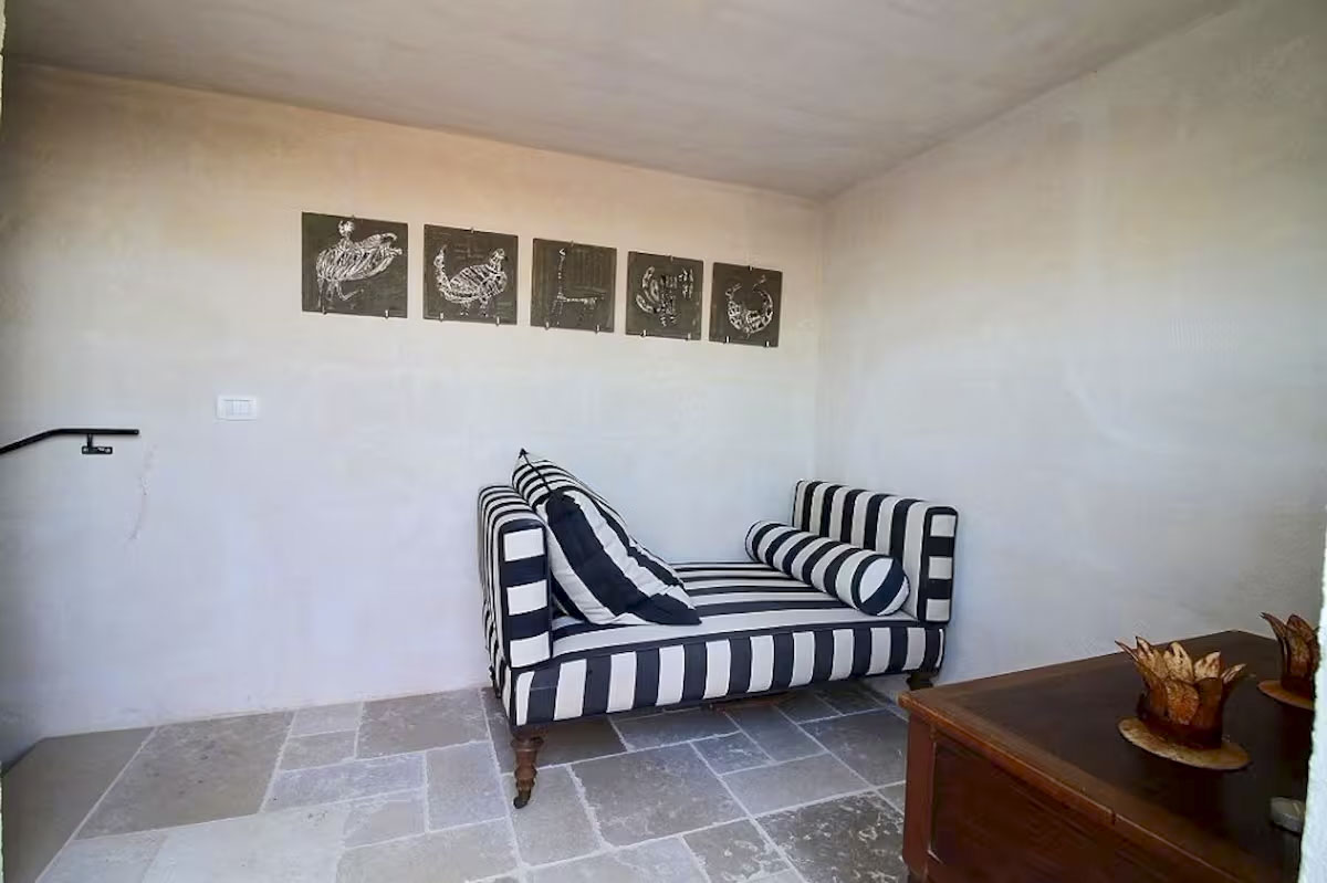 Small lounge or second sleeping area with a stylish black and white striped daybed, dark wooden chest, and framed artwork.