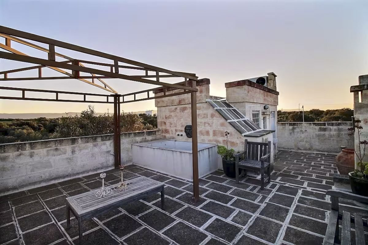 Panoramic rooftop terrace view featuring the built-in tub and the expansive olive groves of the Selva di Fasano landscape.