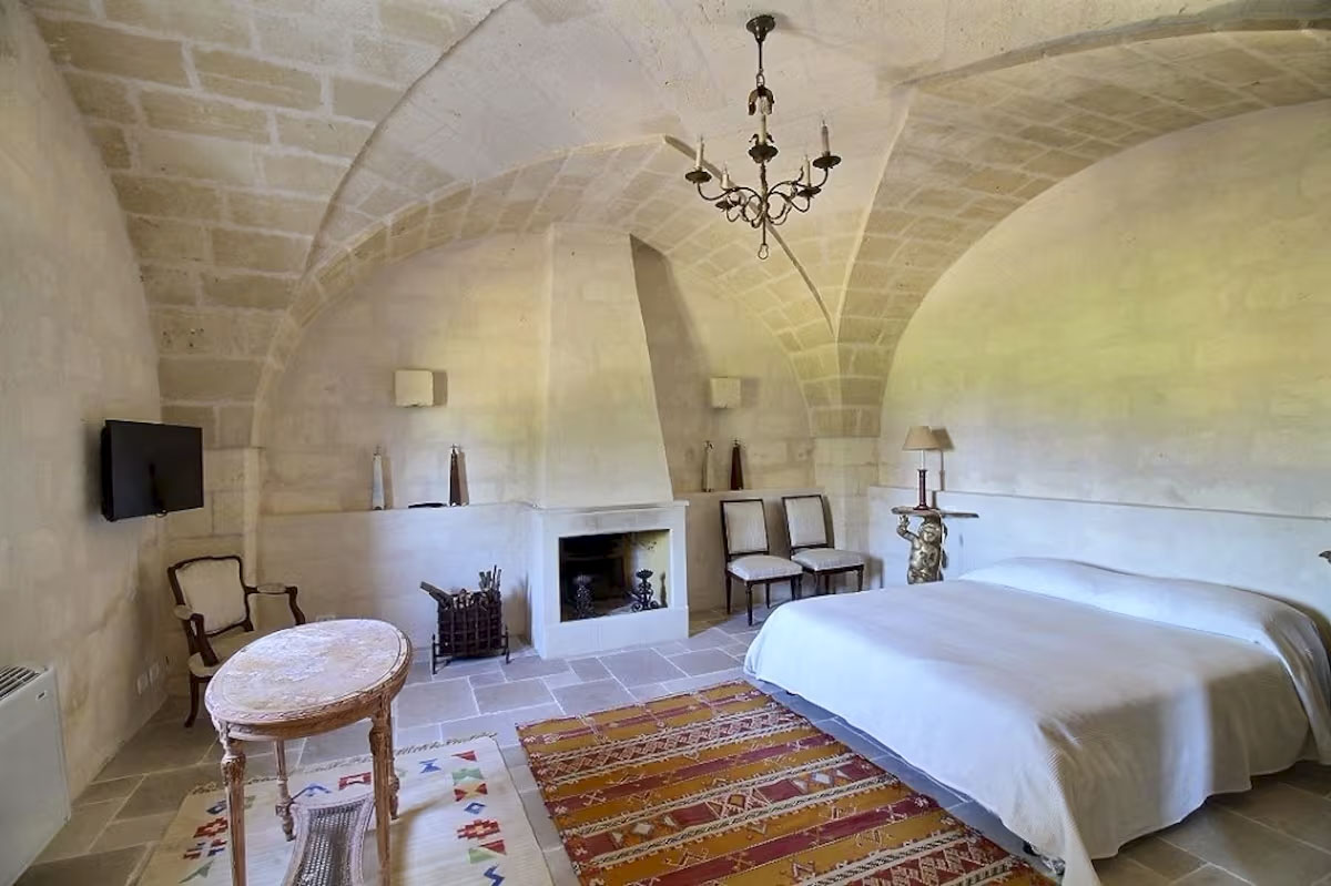 Bedroom with stone vaulted ceiling, built-in fireplace, and double bed in Agriturismo San Virgilio.