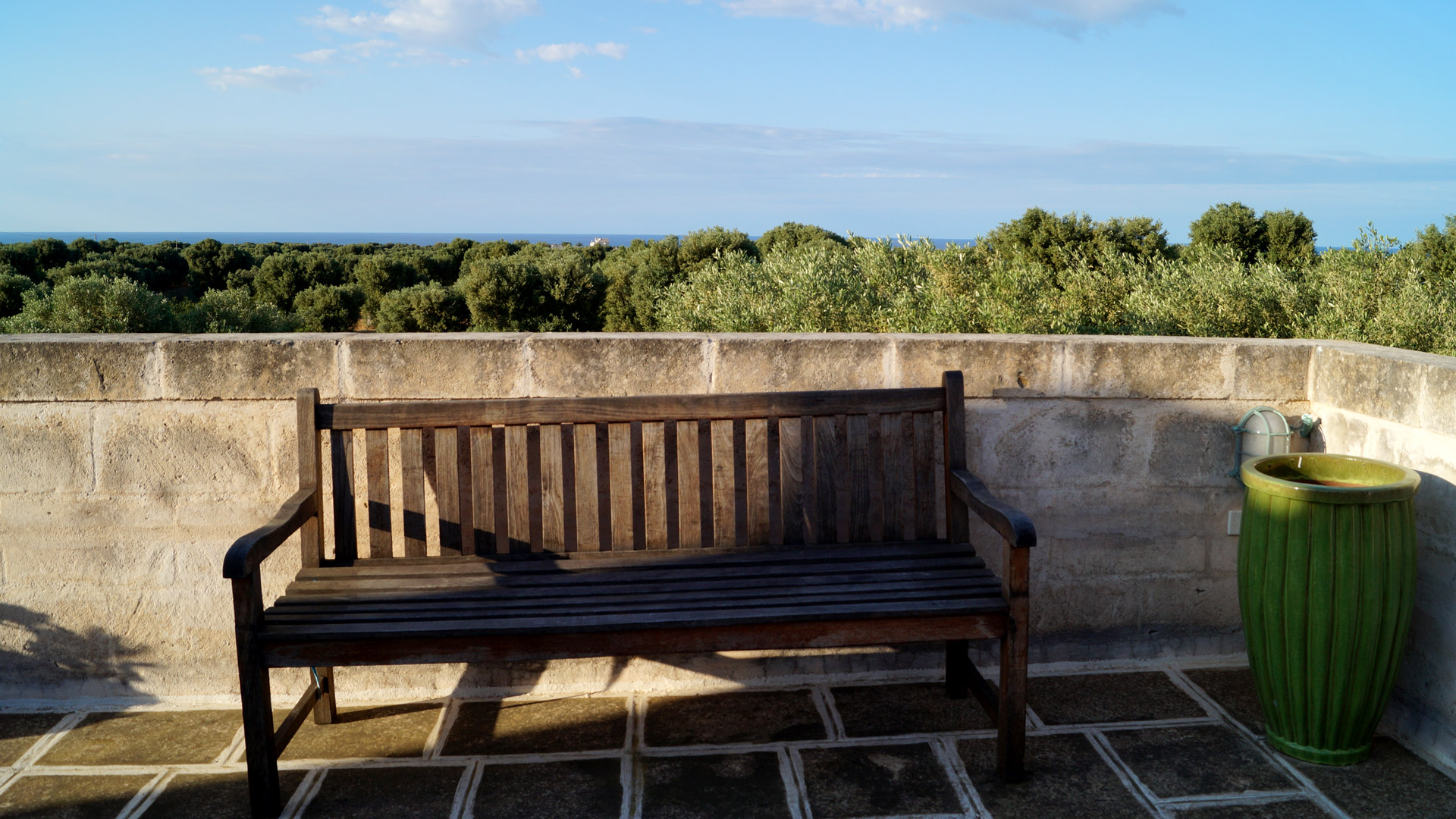 Rooftop terrace of Agriturismo apartment with wooden bench, overlooking Monumetal olive groves and the Adriatic Sea (vista mare).
